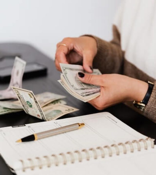 crop-payroll-clerk-counting-money-while-sitting-at-table.jpg